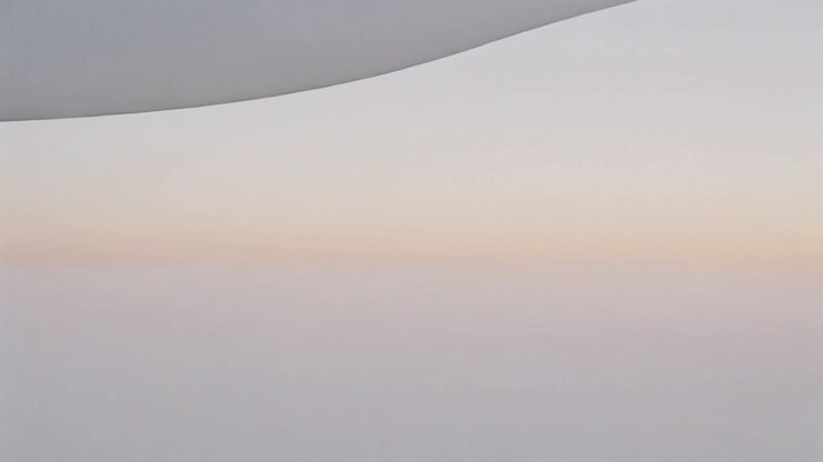 Shifting camera from window revealing wing silhouette over cloud deck, capturing sunrise hues