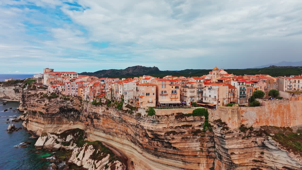 Aerial drone shot over the historic coastal town of Bonifacio in Corsica, France. High view of the rocky steep cliff and the turquoise sea. Ancient Citadel overlooking the rugged coastline
