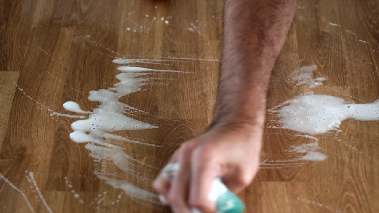 Man&rsquo;s arm washing a new wood table with scouring pad and soap