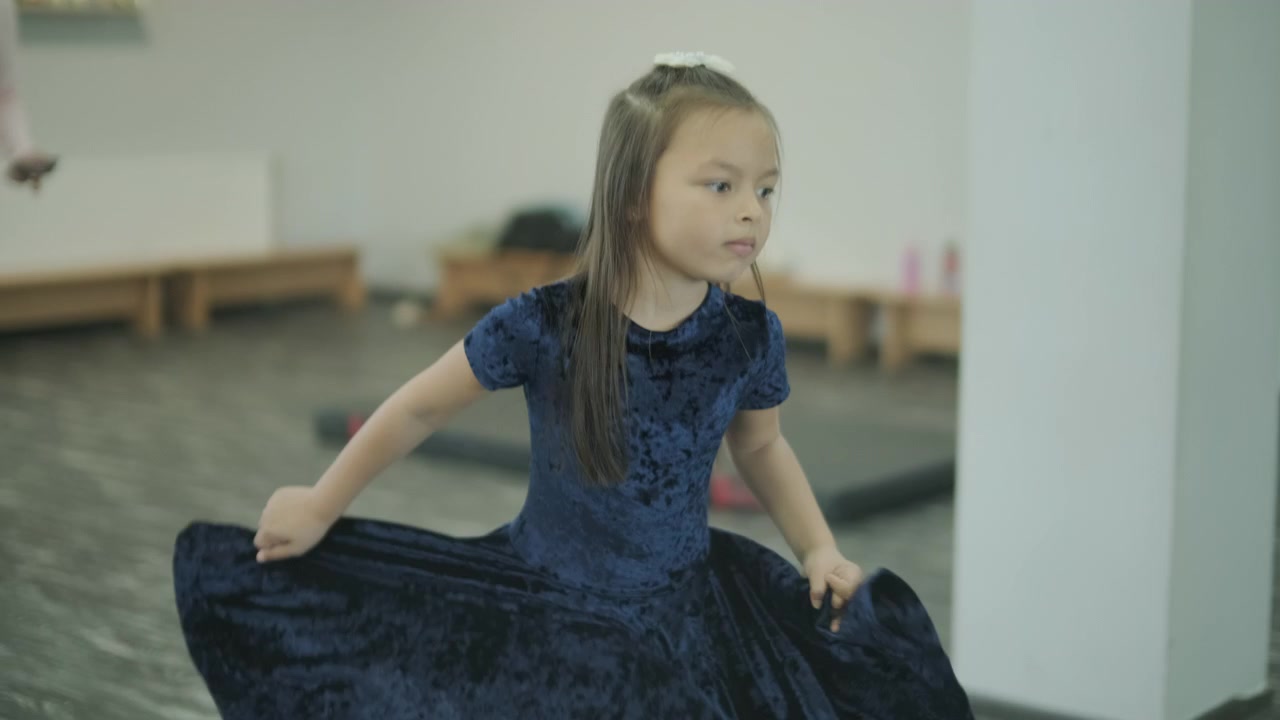 Bambina che balla e volteggia in un vestito di velluto blu
