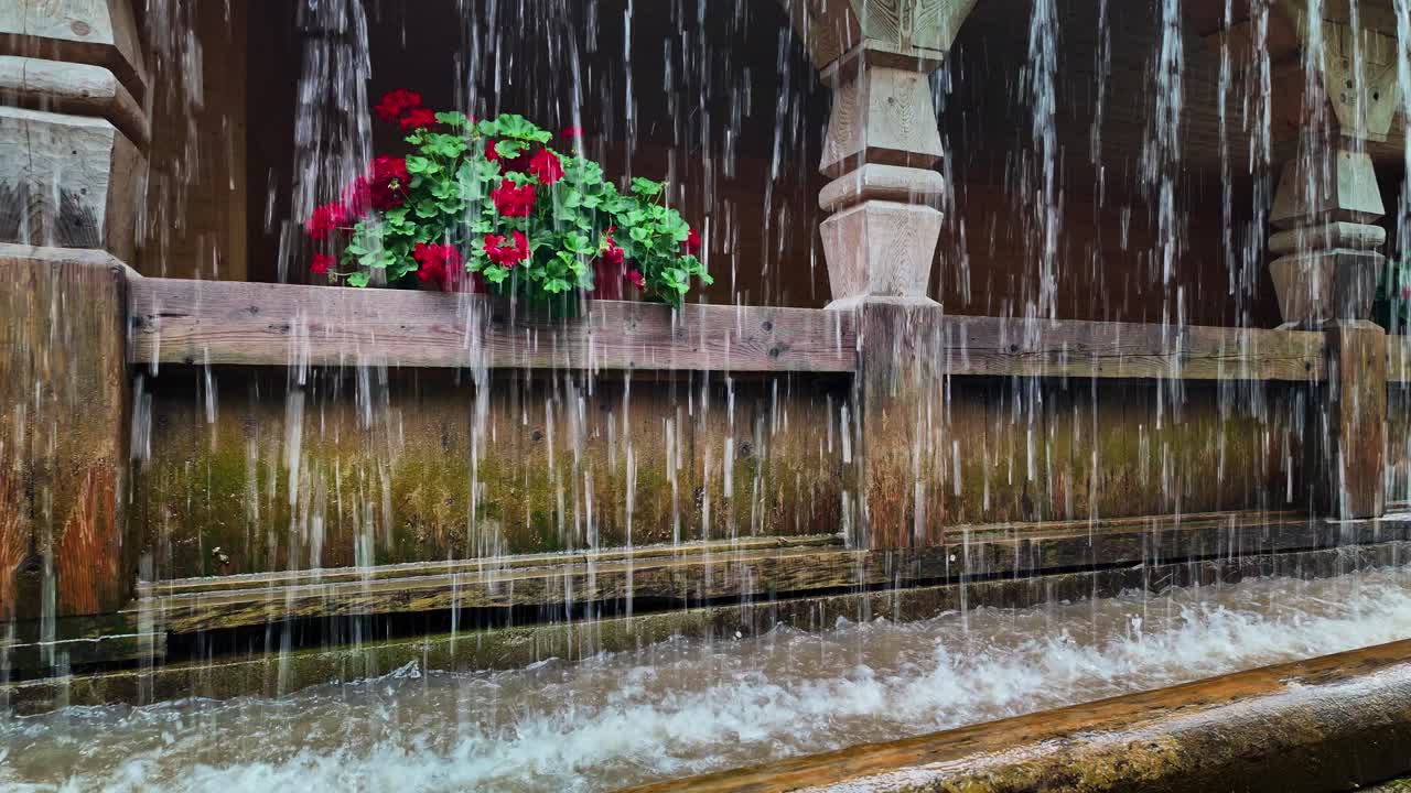Water cascades over rustic carved wood garden pergola architecture