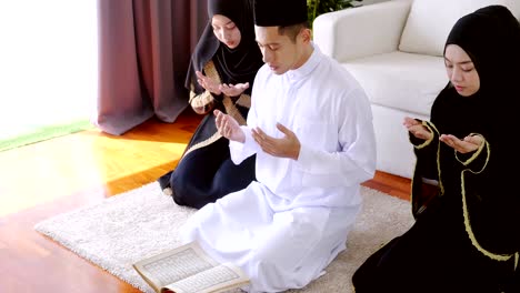 asian young muslim prayers bow to pray for blessings in the living room, belief in islam muslims pray at home daily as a blessing for themselves and their family