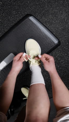 woman tying running shoes in a gym