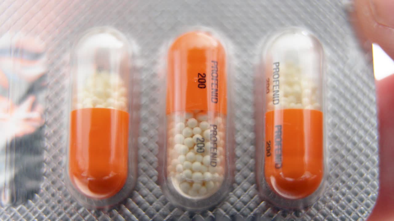 close up of three orange profenid 200mg capsules in blister pack with visible granules