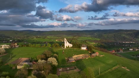 símbolo de la fe: mientras el avión no tripulado se desliza hacia atrás, revela una iglesia moderna en lo alto de una colina bañada por el sol durante una serena noche de primavera, bajo el espectacular dosel de nubes y un cielo azul claro