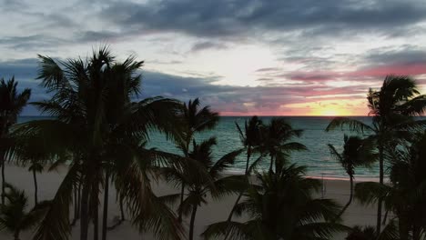 Romantic-sunset,-sunrise-in-Caribbean-sea,-silhouette-palm-trees,-serene-and-sensual-paradise-scene-above-sand-beach-in-Dominican-Republic,-dramatic-cloudscape,-solitude-in-paradise