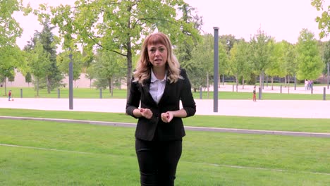 una hermosa chica con cabello rubio largo en un traje de negocios da una entrevista. blogger. periodista. noticias. una joven mujer de negocios da entrevistas sobre su compañía a los periodistas. una entrevista en un parque en la calle