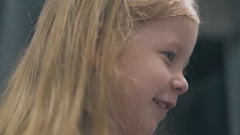 little-girl-looks-at-mirror-posing-in-light-room-close-view