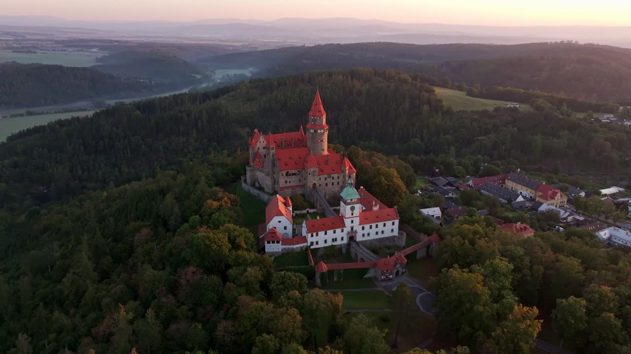 Dronebilde av Bouzov slott idét daggryet bryter frem over det tsjekkiske landskapet.