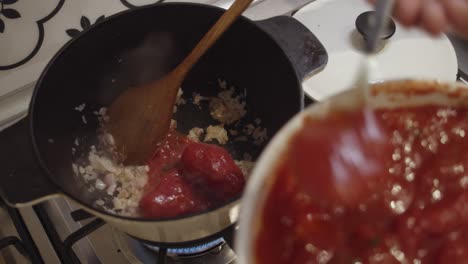 adding fresh tomato sauce into cooking hot pot on a gas stove