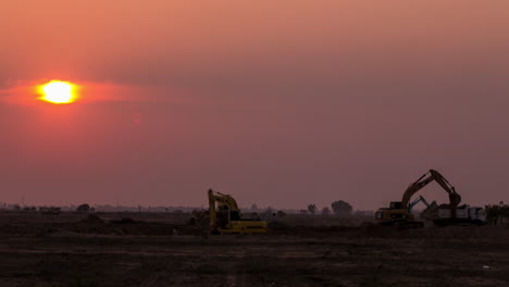 Silhouette-of-excavators-digging-in-golden-setting-sun,-copyspace