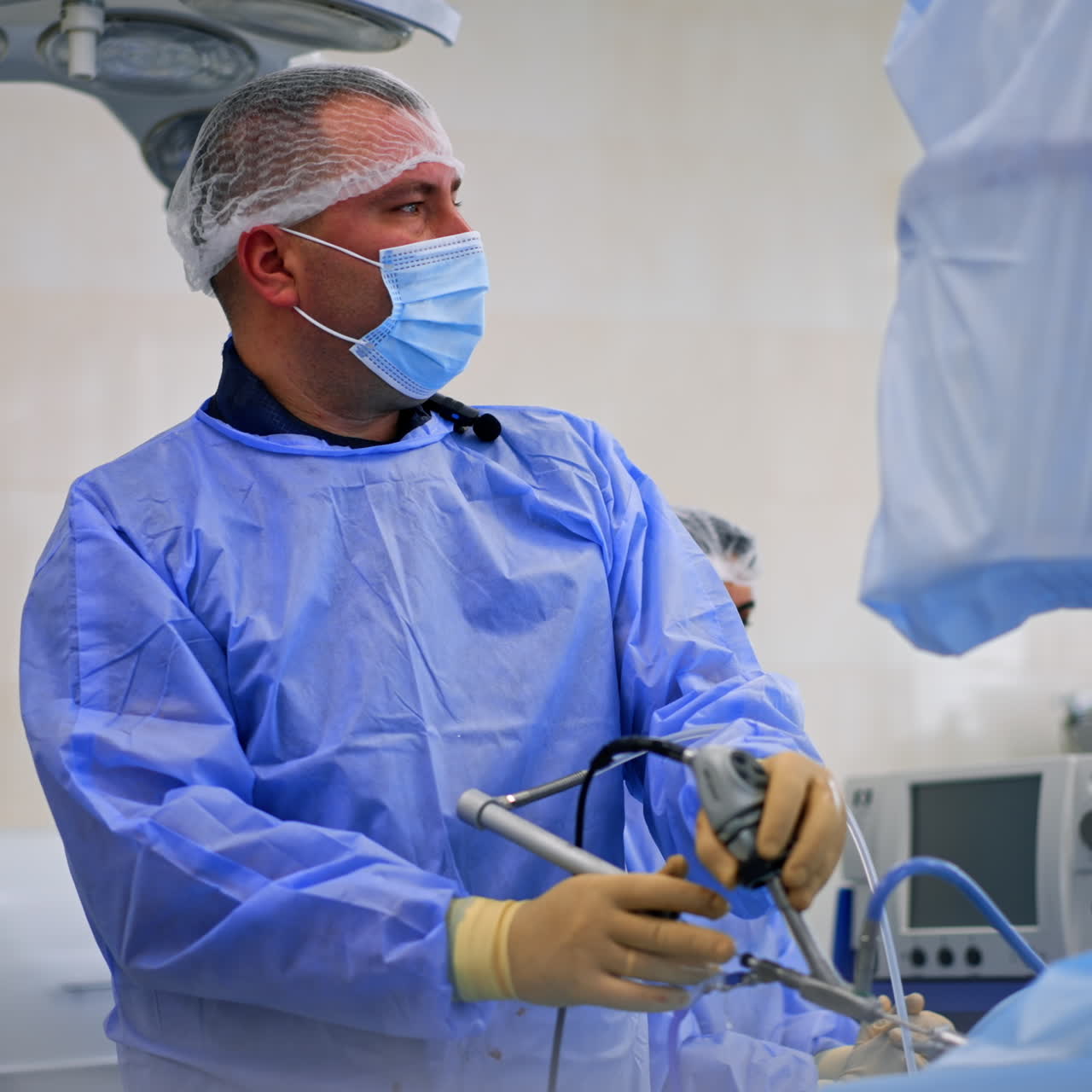 Attentive male Caucasian surgeon looking at the screen using surgical device. Endoscopic surgery in hospital.