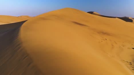 aerial view flying over sunlit sand dunes in the namib desert, sunset in namibia