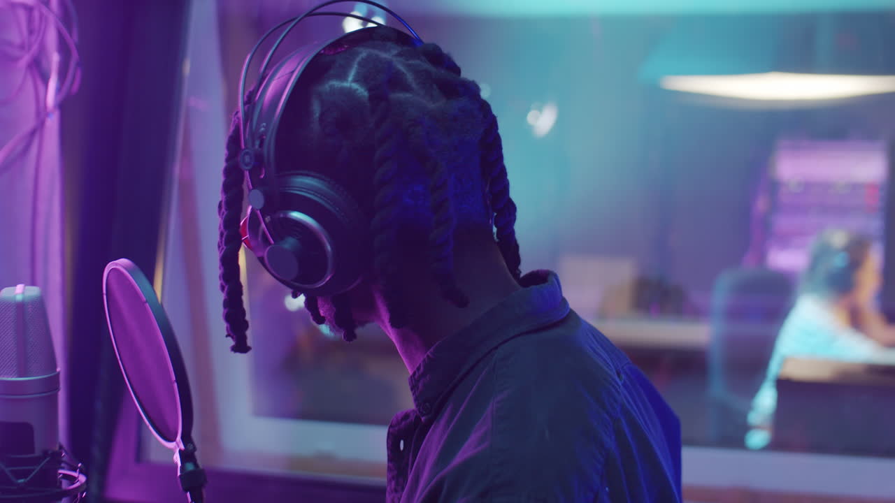 hombre afroamericano grabando una canción de rap en un estudio de producción de audio