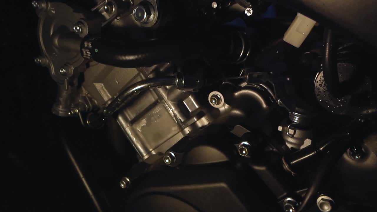 Close up video orbiting and gliding over a gorgeous pristine and new motorcycle mechanical motor with different part clearly visible. Night or evening time and shallow depth of field, bokeh background