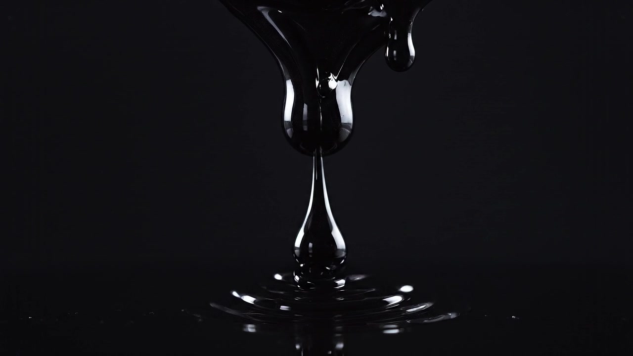 Close-up minyak gelap reflektif dengan latar belakang hitam