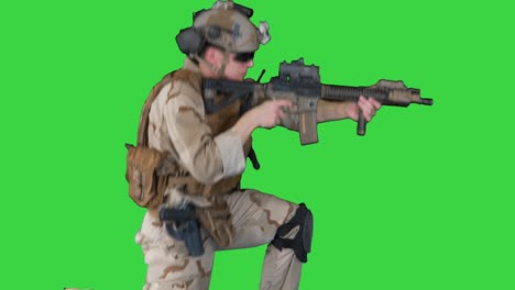 paratrooper in uniform shooting from sitting position on a green screen, chroma key