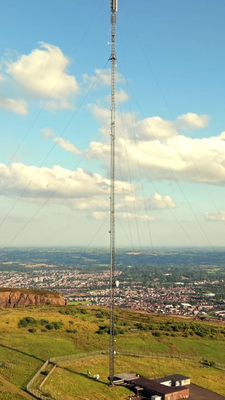 Video aéreo en primer plano de la Torre Transmisora de Televisión de Black Mountain en Belfast Occidental, Irlanda del Norte, en una luminosa tarde de verano, producido a 60 FPS, con relación social 1080x1920 y color Rec709