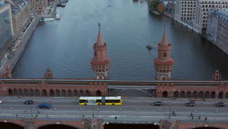 Oberbaumbrücke-In-Berlin,-Deutschland-Und-Gelber-Bus,-Der-Bei-Tageslicht-über-Die-Spree-Fährt,-Antenne-Nach-Unten-Kippen,-Weit-Nach-Vorne