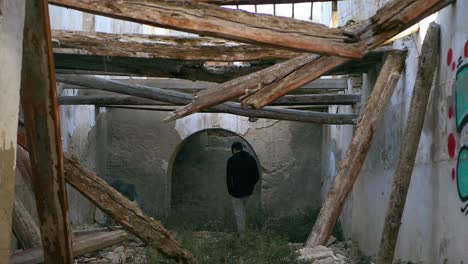 un joven, adolescente, camina por un lugar abandonado con vigas derrumbadas