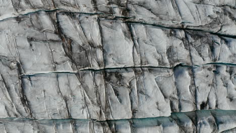 Overhead-view-of-snowy-icy-formation-of-Breidamerkurjokull-glacier-in-Vatnajokull-National-Park.-Top-down-view-of-icy-cracked-formation-of-glacier-in-Iceland.-Nature-pattern.-Beauty-on-earth