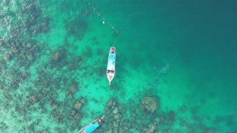 long-tail tour boats at reef in emerald clear water, aerial reveal