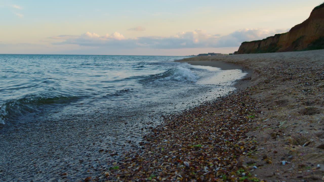 Sea beach at sunset. Ocean water waves splashing sand coast. Nature background