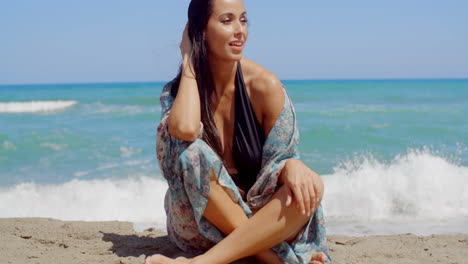 Mujer-Atractiva-Sonriente-Sentada-En-La-Arena-De-La-Playa