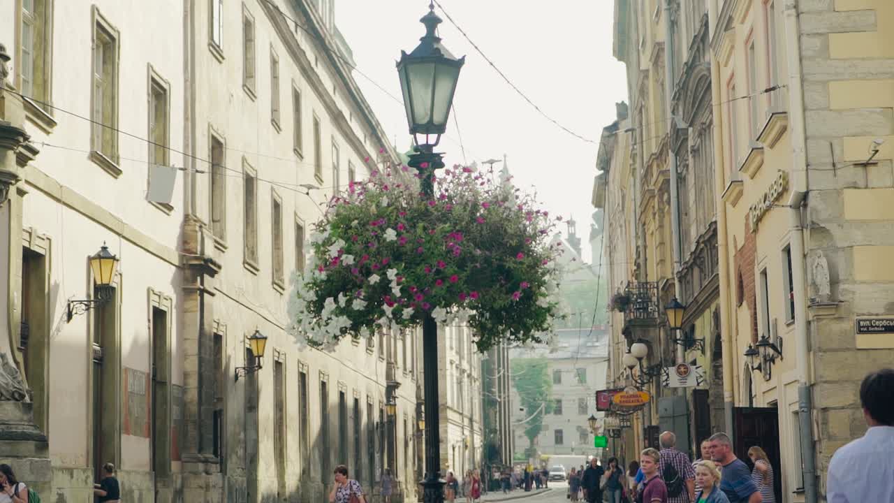 Central part of old Lviv with pedesrians and red tram going by. Beautiful view of architectural buildings and transport in ancient town outdoors.