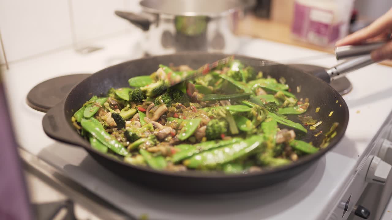 Woman cooking wok with mushrooms, brocolli, chili, noodles, leek, suger peas and soy-3