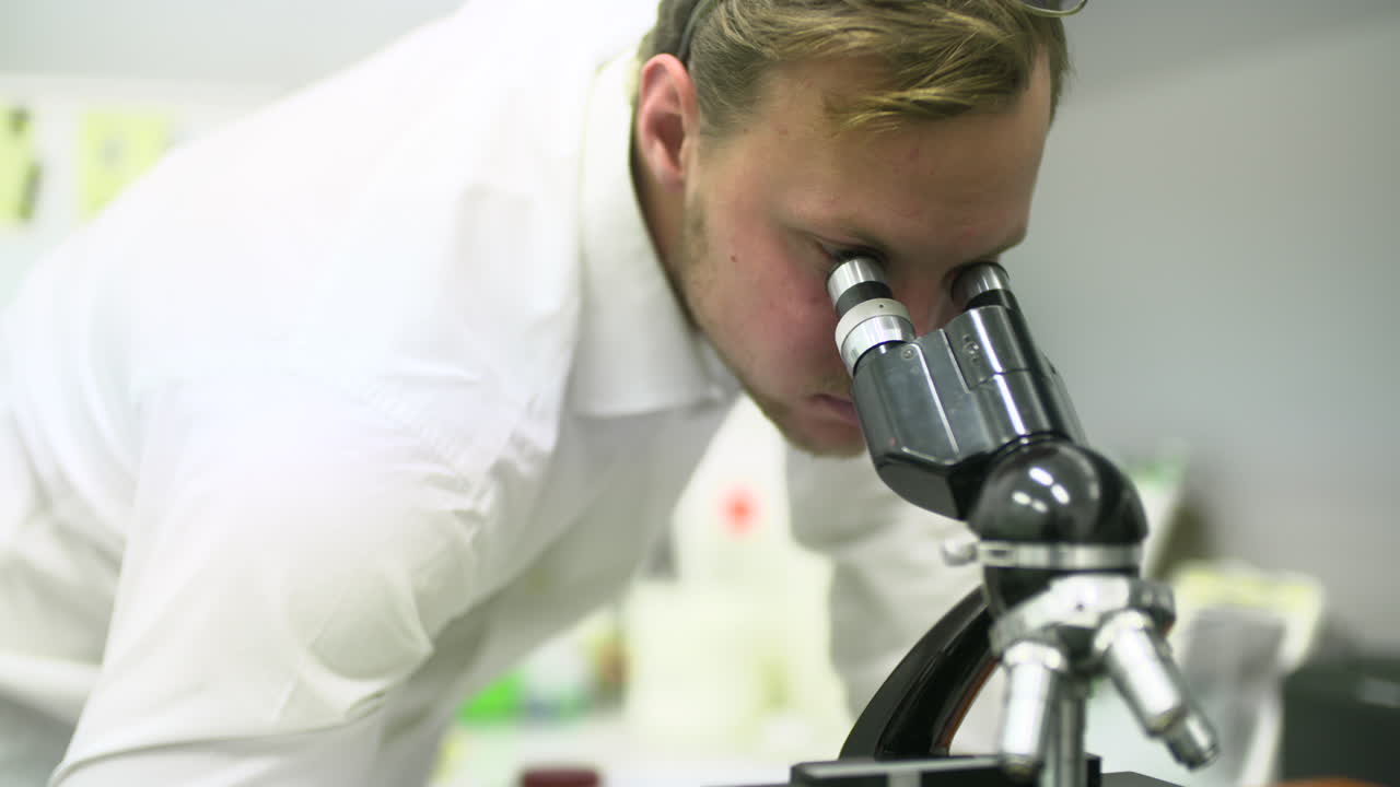 Man Looking into Microscope in Laboratory