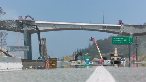 wide view of heavy equipment tearing down part of a bridge over the 405 freeway in los angles 1