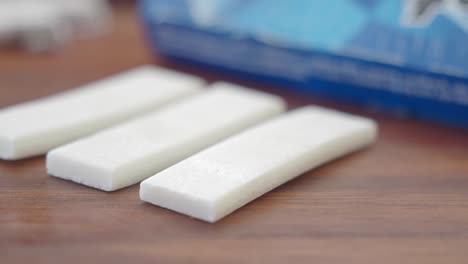 three white chewing gum sticks on a wooden surface
