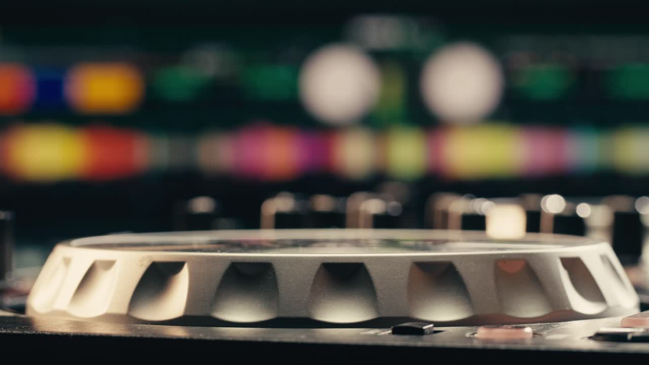 Detailed shot of a DJ's hand turning a knob on a mixer during a live performance, focusing on the equipment.