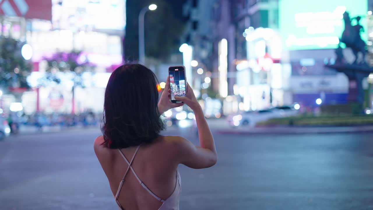 Woman taking a photo at night in the city