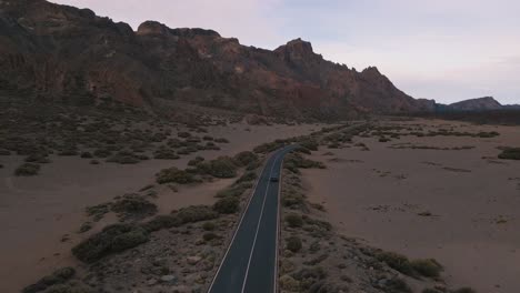 Schöne-Tracking-Drohne-Aufnahme-Von-Bergen-Und-Blauem-Lieferwagen,-Der-Die-Autobahn-Hinunterfährt,-Teneriffa,-Spanien