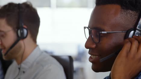 Side-view-of-young-cool-mixed-race-call-center-team-calling-and-sitting-at-desk-of-modern-office-4k