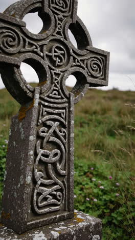 close-up of an ancient celtic cross with intricate carvings in a grassy landscape