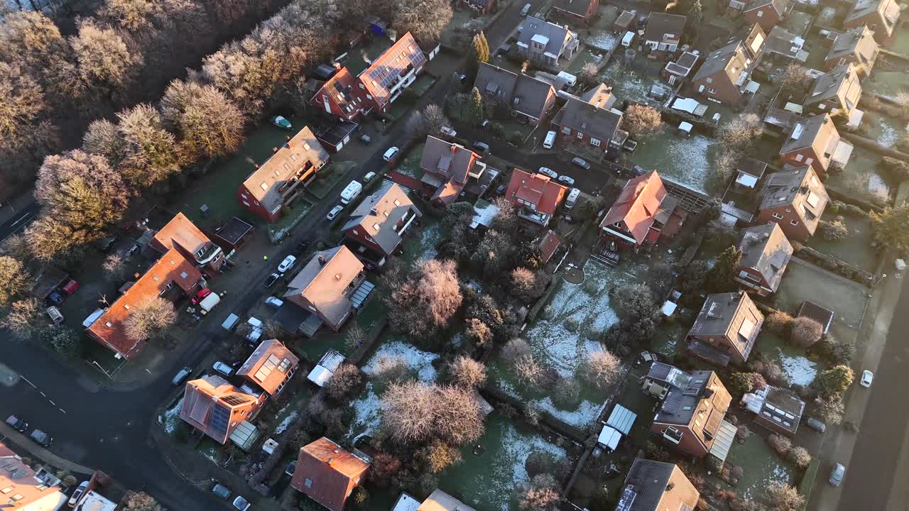 Frozen and icy neighborhood during golden sunrise. Frozen leafless trees in winter season. Aerial top down flyover. Single family houses and frosty rooftops in america. Quaint suburb district.