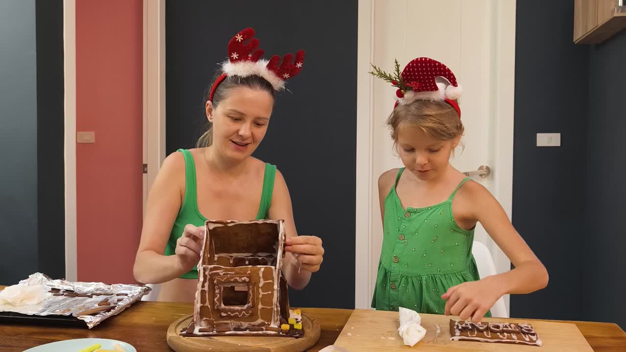 madre e hija decorando una casa de pan de jengibre