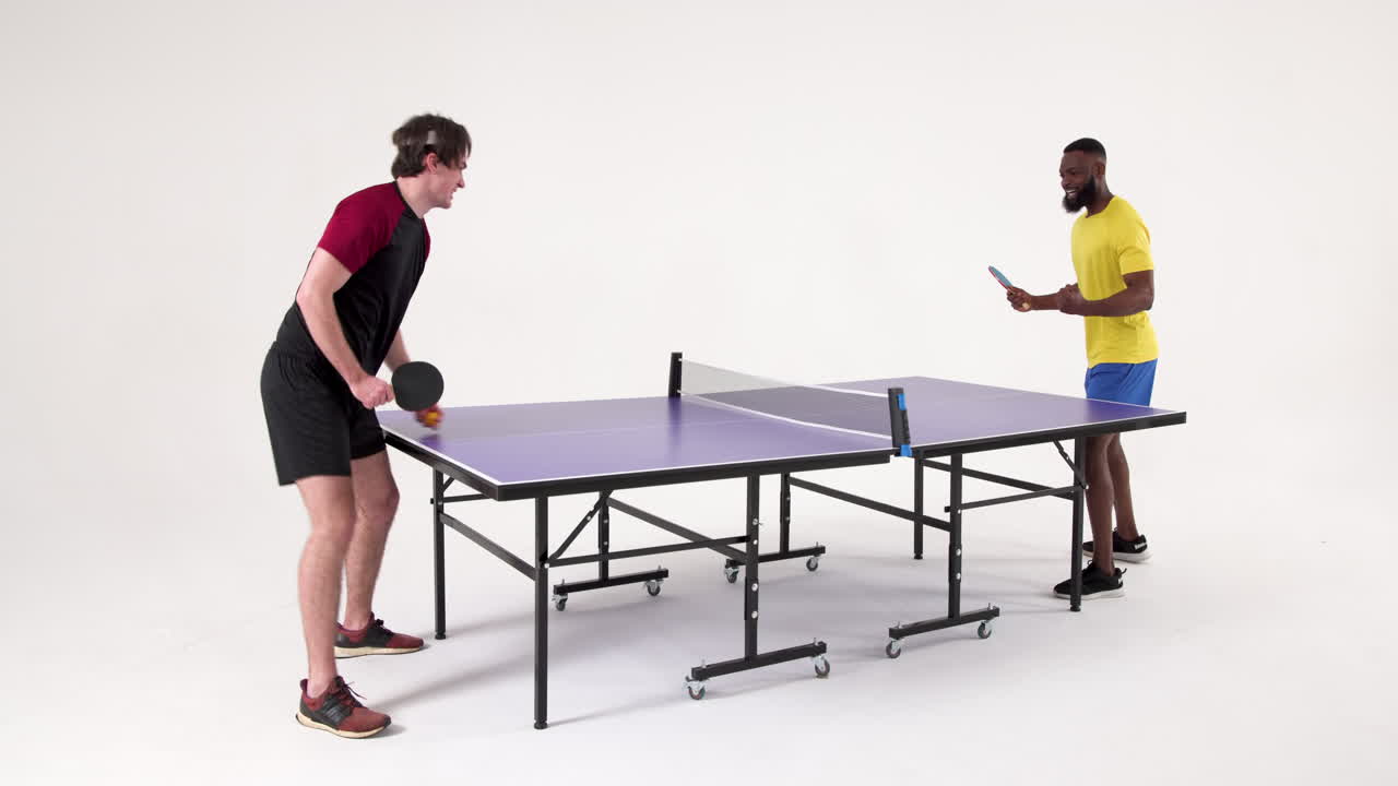 Playing table tennis, two men competing in friendly match indoors