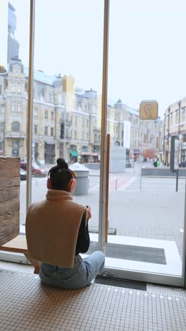 woman enjoying coffee in a cozy cafe with city view