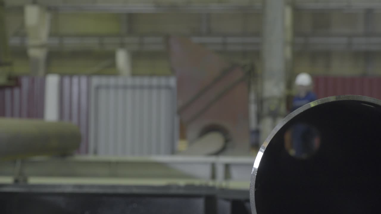 공장에서 금속 파이프를 칠하는 산업 노동자