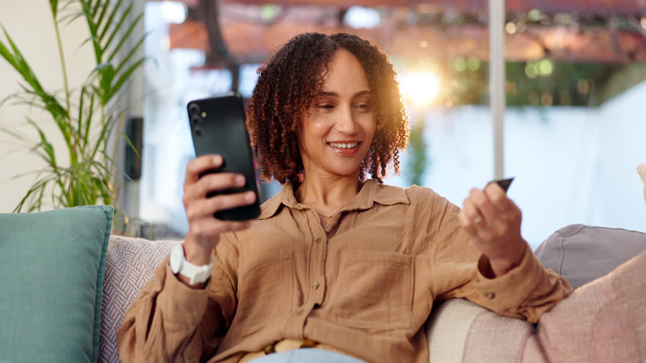 Woman using mobile phone and credit card for online shopping at home
