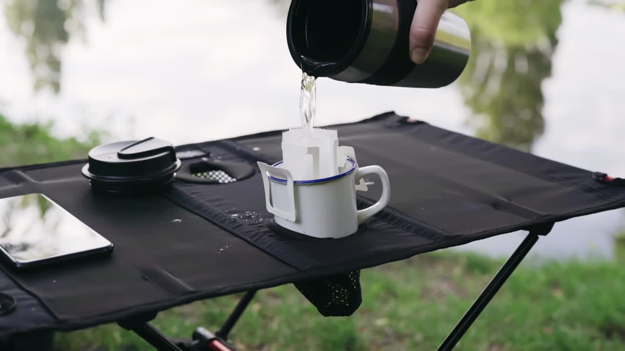 Pouring hot water through drip coffee bag outdoors