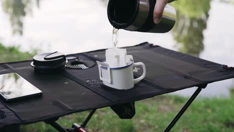pouring hot water through drip coffee bag outdoors