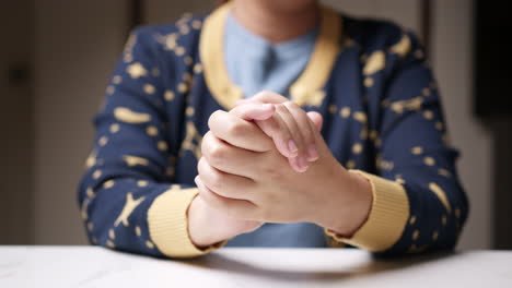 close-up of hands clasped together while squeezing each finger one by one, massaging them gently to relieve it from pain