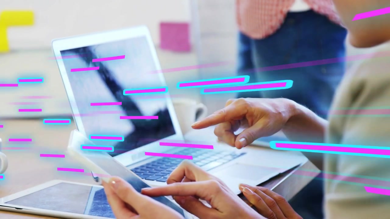 Donna con gli occhiali che indica il laptop, mentre un collega usa il telefono, con strisce magenta o ciano che guidano il design.