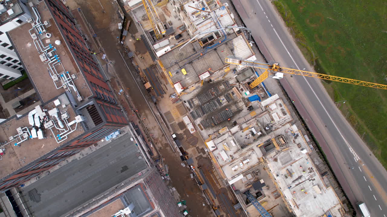 drone de arriba hacia abajo vista giratoria por encima de las grúas de construcción en el sitio de construcción de rascacielos