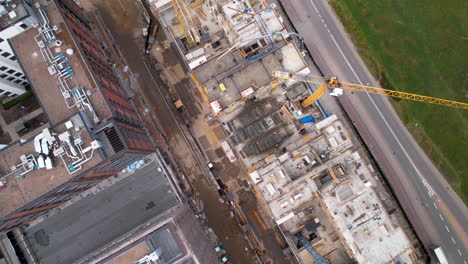 Vista-Giratoria-De-Arriba-Hacia-Abajo-De-Drones-Sobre-Grúas-De-Construcción-En-El-Rascacielos-Del-Edificio-Del-Sitio